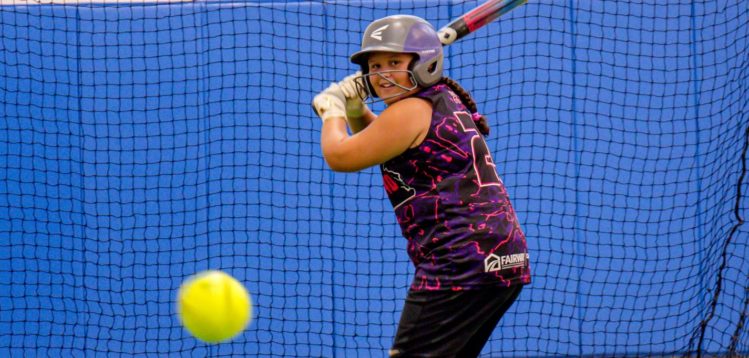 A youth softball player prepares to hit a ball inside the batting cage at PATH Recreation & Fitness Center.